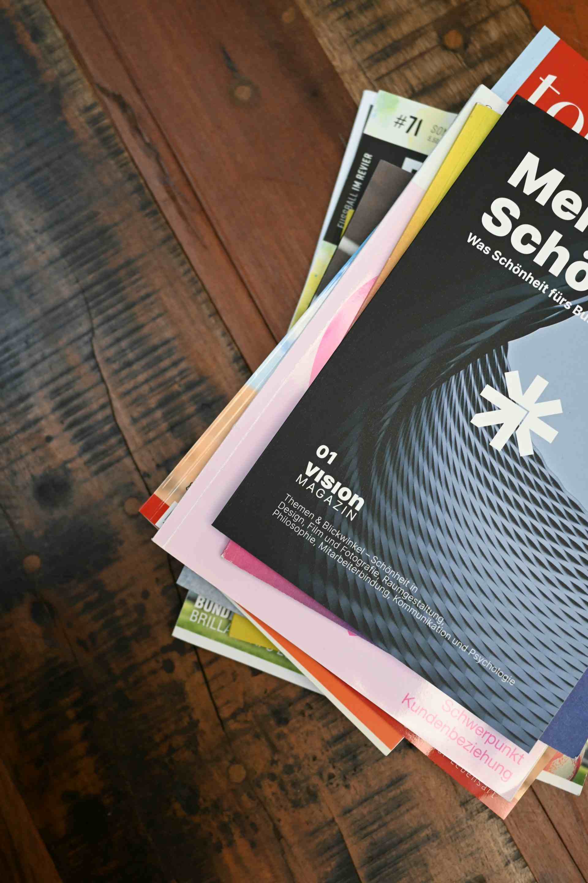 Ein Stapel Bücher liegt auf einem Holztisch.